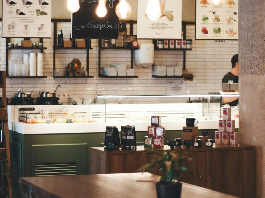 Cafe counter with hanging bulbs, stacked cups and a pastry case