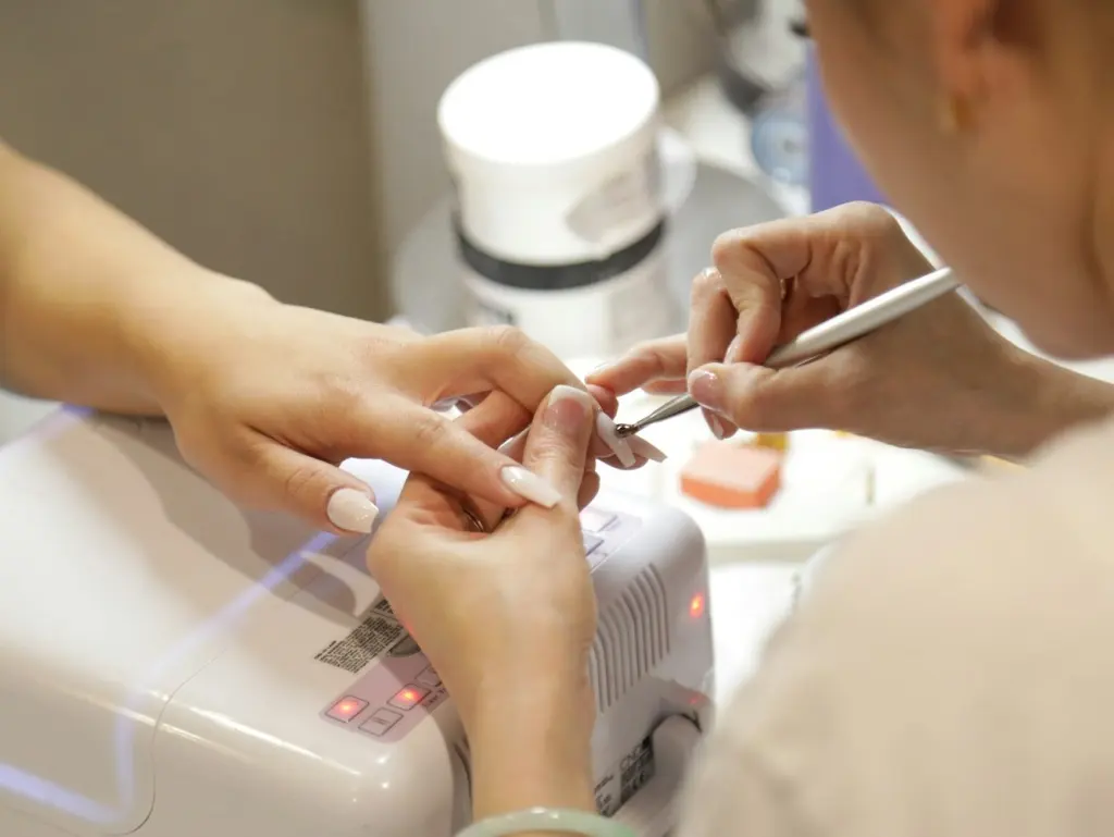 Manicure in progress at a nail studio, lamp switched on