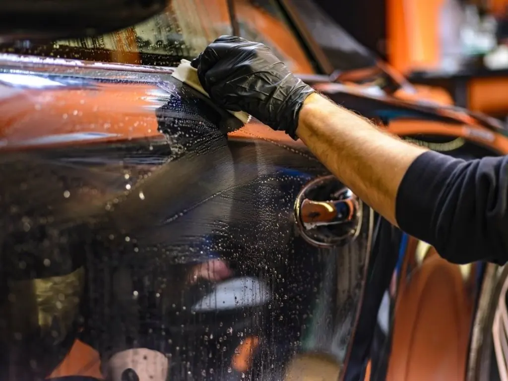 Car body hand-polished with a mitt in a detailing bay