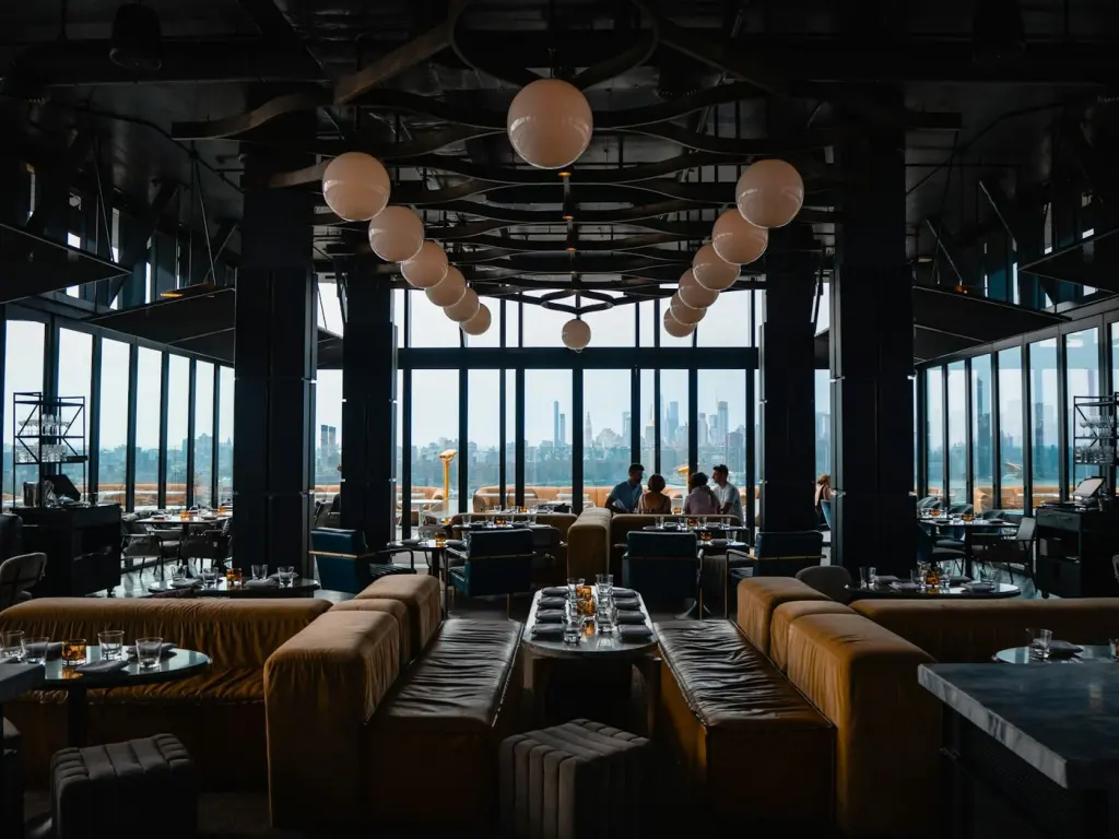 Restaurant dining room set for evening service, windows onto the city